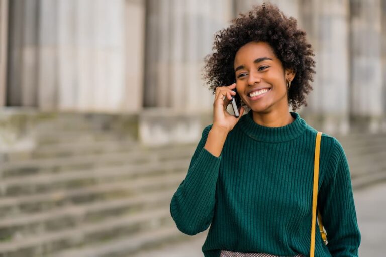 Une jeune femme parlant au téléphone devant un immeuble.